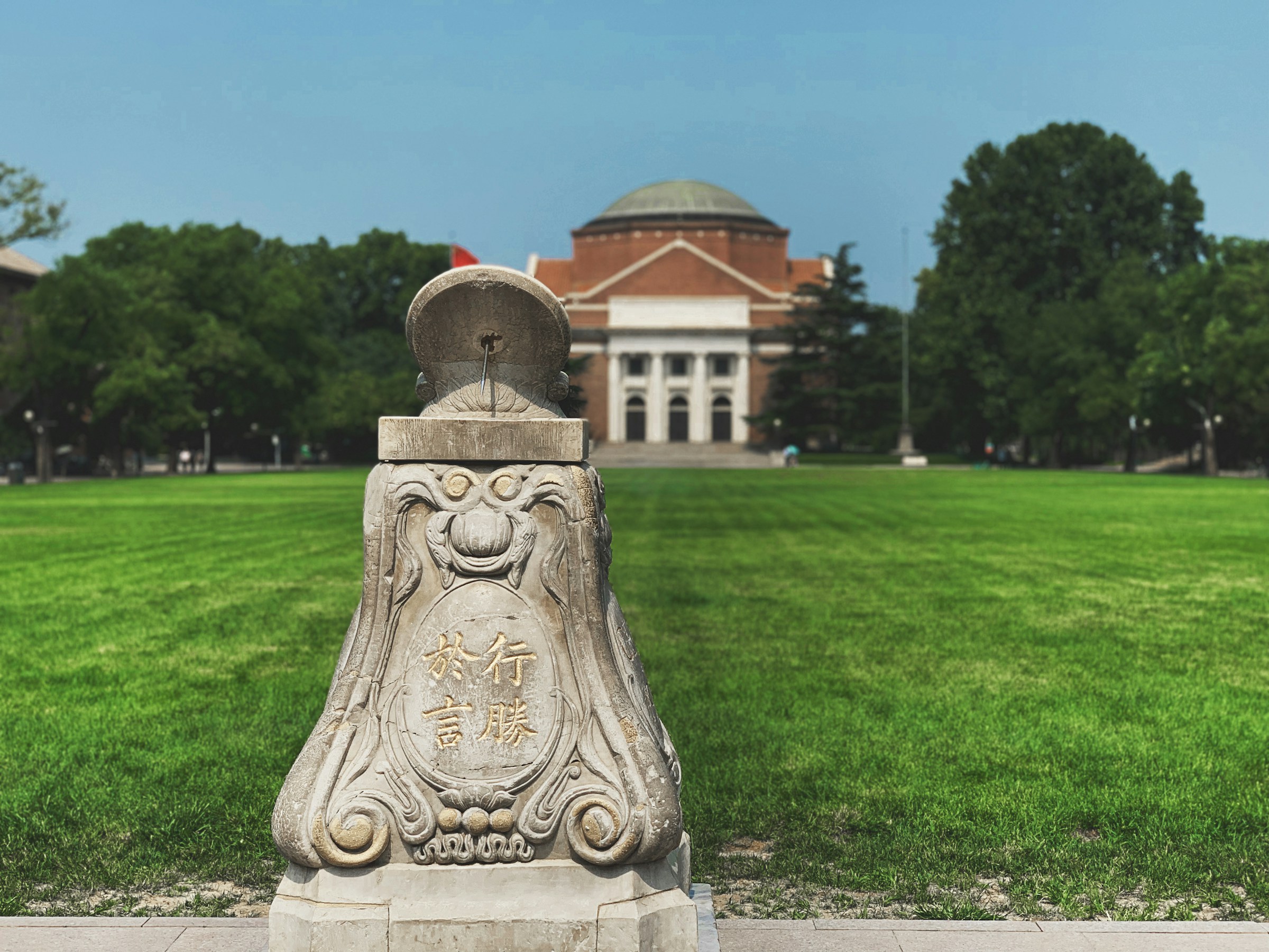 A stone sundial on the lawn in front of the Tsinghua University auditorium